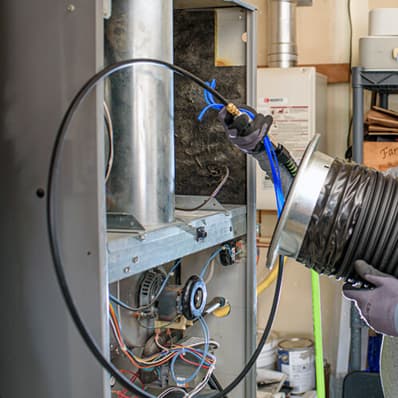 A Totally Clean technician cleaning a residential furnace and duct system